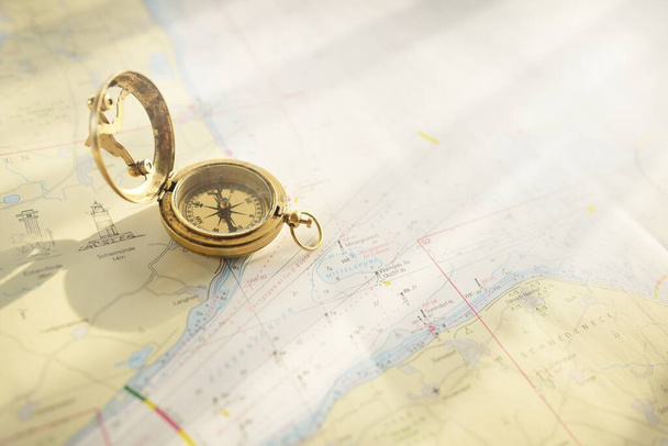 Retro style antique golden compass (sundial) and old nautical chart close-up. Vintage still life. Sailing accessories. Wanderlust, travel and navigation theme. Graphic resources, copy space - Фото, зображення