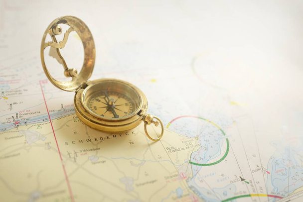 Retro style antique golden compass (sundial) and old nautical chart close-up. Vintage still life. Sailing accessories. Wanderlust, travel and navigation theme. Graphic resources, copy space - Photo, image