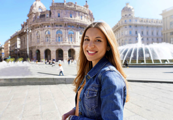 Jeune femme souriante portant une veste en denim bleu dans la ville historique en regardant la caméra - Photo, image