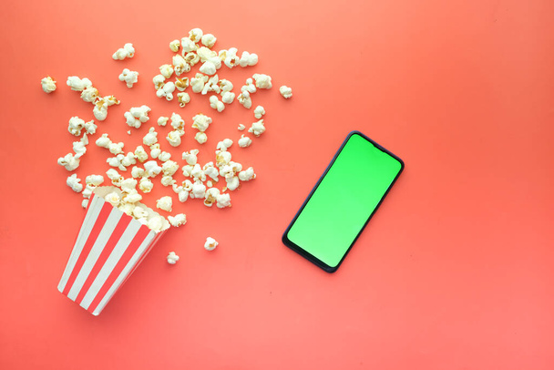 bovenaanzicht van smartphone en popcorn op tafel  - Foto, afbeelding