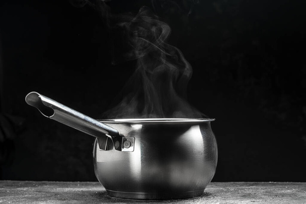 vapor sobre olla de cocina sobre fondo negro, comida caliente. Tazón de vapor caliente con humo, Culinario, cocina, concepto, - Foto, Imagen