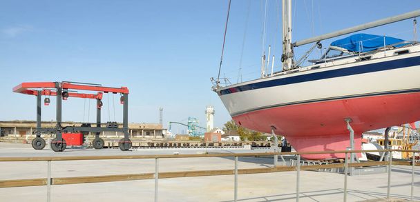Bir yat limanında karada duran 20 metrelik bir yelkenli. Ulaşım, denizcilik, onarım ve hizmet, yelkencilik, spor, eğlence. Turizm, boş zaman aktivitesi kavramları - Fotoğraf, Görsel