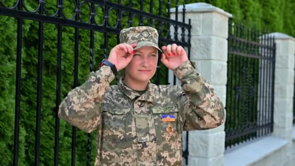 Hermosa chica soldado del ejército ucraniano sonríe. Mirando la cámara mostrando el éxito. Concepto de guerra - Metraje, vídeo