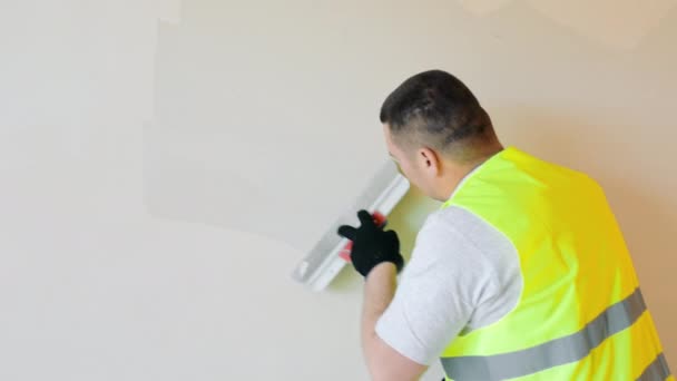 Repair work in the room. Plasterer painter construction worker plasters the wall with a plaster spatula. Plastering and leveling of unevenness on a wall by means of finishing plaster. - Séquence, vidéo