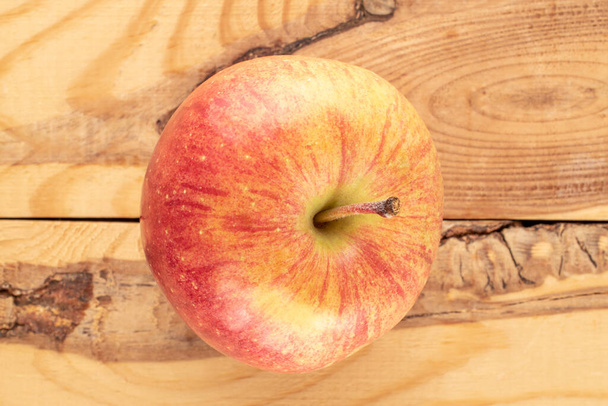 Una mela biologica rossa su un tavolo di legno, primo piano, vista dall'alto. - Foto, immagini