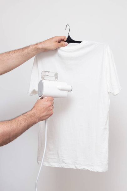 Manual garment steamer T-shirt steam on a white background - Foto, imagen