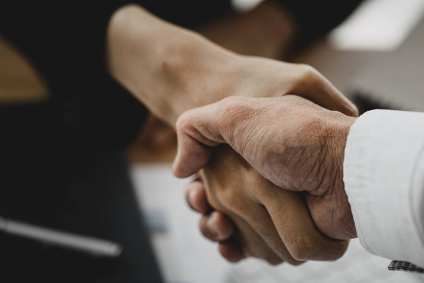 Close-up two business men holding hands, Two businessmen are agreeing on business together and shaking hands after a successful negotiation. Handshaking is a Western greeting or congratulation. - Фото, изображение
