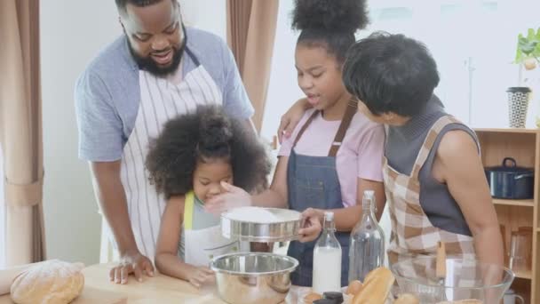 African America family wearing apron for cooking bakery or bread with flour together in the kitchen at home, parent and little child preparing food with fun and playful, relationship and hobby. - Кадры, видео