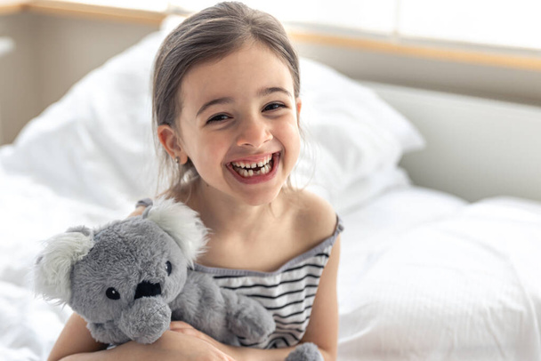 Feliz niña con juguete suave koala en la cama. - Foto, Imagen