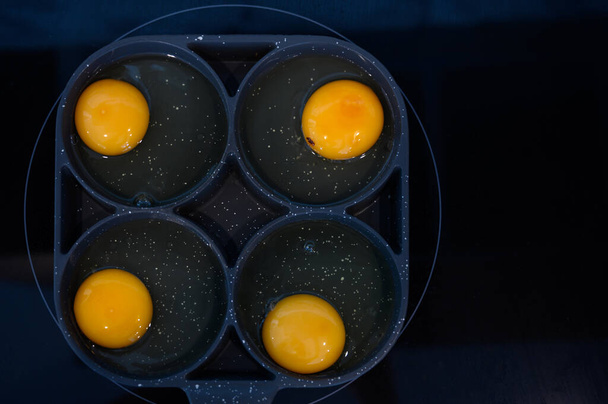 Vista superior de fazer ovos fritos na frigideira preta no fogão elétrico para o café da manhã - Foto, Imagem