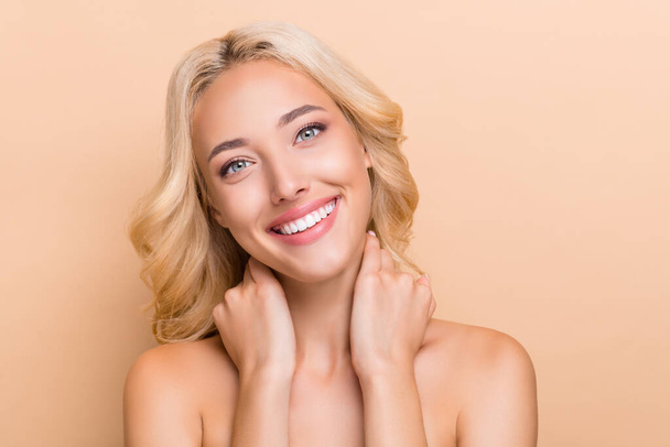 Portrait of attractive cheery shine wavy-haired girl touching pure neck daily domestic procedure isolated over beige pastel color background - 写真・画像