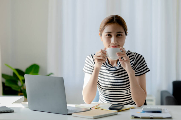 Asian woman drinking coffee after class makes me drowsy, she is a university student, The concept of online learning due to the COVID-19 outbreak to prevent an outbreak in the classroom. - Foto, imagen