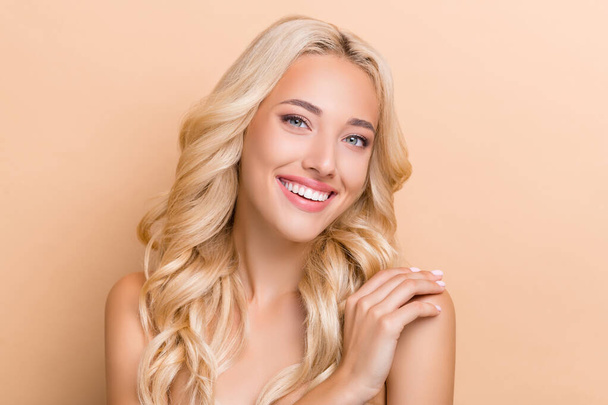 Portrait of attractive healthy cheerful wavy-haired girl touching shoulder scrub exfoliation isolated over beige pastel color background - Photo, Image