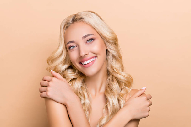 Portrait of attractive cheery wavy-haired girl touching smooth shoulders fresh shower isolated over beige pastel color background - Foto, immagini