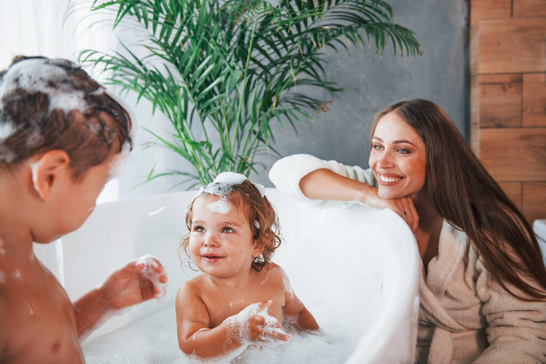 Having fun. Young mother helps her son and daughter. Two kids washing in the bath. - Fotoğraf, Görsel