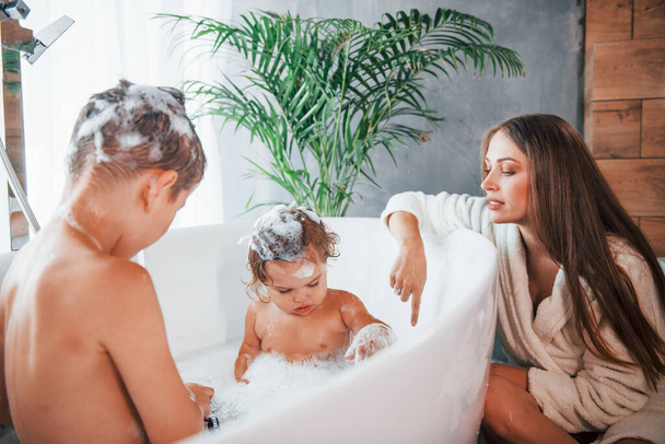 Having fun. Young mother helps her son and daughter. Two kids washing in the bath. - Fotoğraf, Görsel