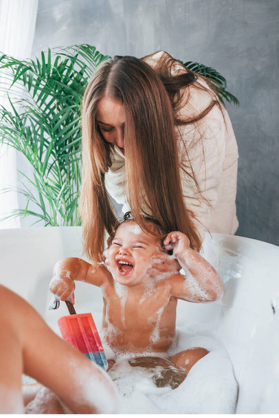 Having fun. Young mother helps her son and daughter. Two kids washing in the bath. - Fotografie, Obrázek