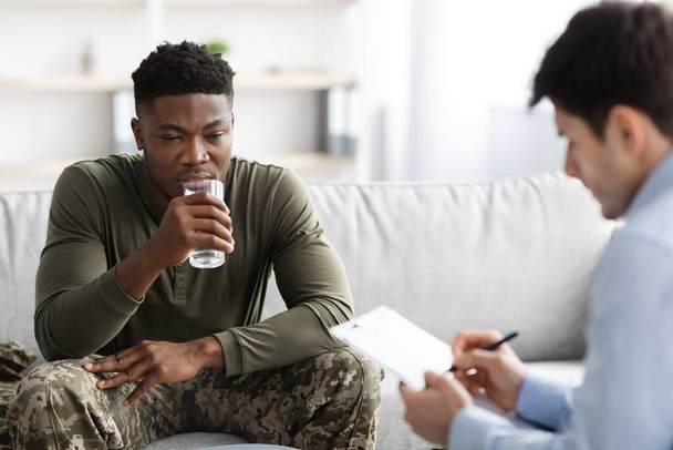 Soldado afroamericano teniendo sesión de terapia con psicólogo, interior de la clínica - Foto, imagen
