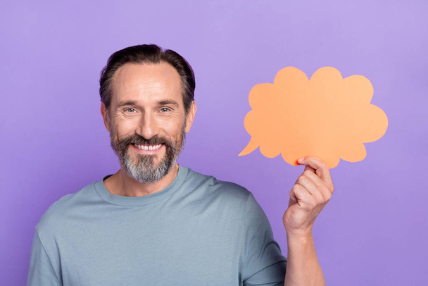 Portrait of cheerful handsome middle aged man hold speech bubble tell interesting news isolated on purple color background - Foto, immagini