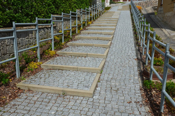 the staircase is divided into stairs and a ramp for wheelchairs. Galvanized tube railings. Granite pavement in the street. - Zdjęcie, obraz