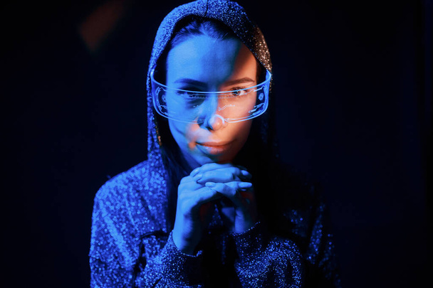 Portrait of young girl that is in eyeglasses in blue neon lighting. - Фото, изображение