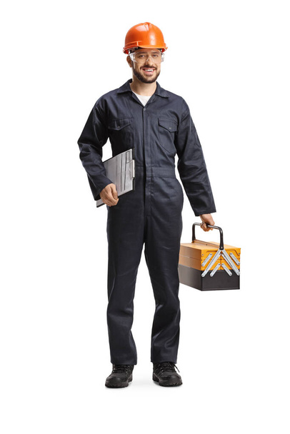 Factory worker in a uniform holding a tool box and a clipboard isolated on white background - Fotoğraf, Görsel