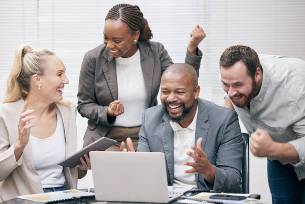 Yes, we did it. Cropped shot of a group of white collar businesspeople cheering while gathered around a laptop in the boardroom. - Foto, immagini