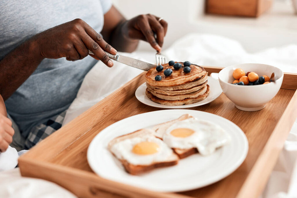 Everything youll need to start the day with right. Shot of an unrecognizable couple enjoying breakfast in bed together at home during the day. - Фото, изображение