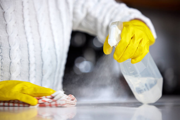 Always use a strong disinfectant. Shot of a woman spraying her kitchen counter to clean it. - Photo, Image