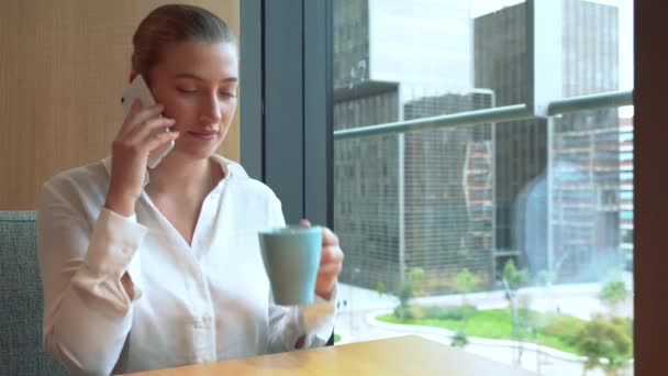 Γυναίκα στέλεχος μιλάει στο κινητό ενώ πίνει καφέ στη δουλειά. 4ια - Πλάνα, βίντεο