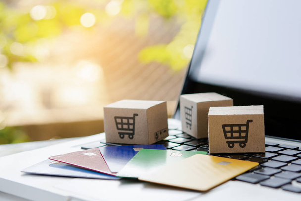 Online vásárlás. Hitelkártya és kartondoboz bevásárlókosár logóval a laptop billentyűzetén. Bevásárlási szolgáltatás az interneten. házhozszállítás - Fotó, kép
