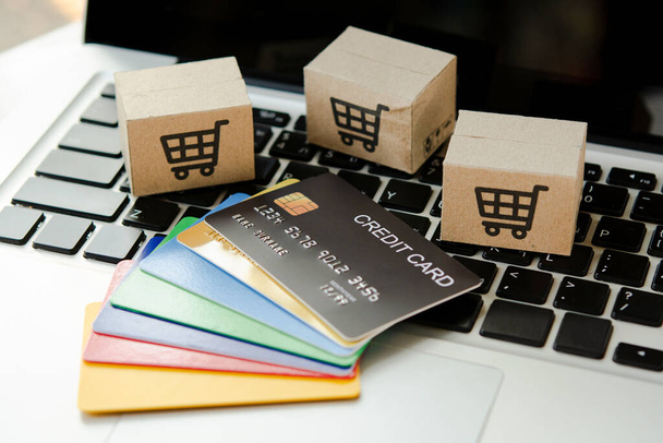 Online einkaufen. Kreditkarten- und Kartonschachtel mit einem Warenkorb-Logo auf der Laptop-Tastatur. Shopping-Service im Internet. bietet Lieferung nach Hause - Foto, Bild