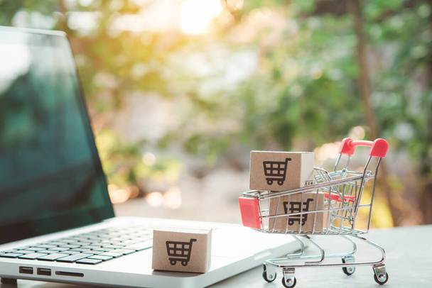 Online einkaufen. Karton mit einem Warenkorb-Logo in einem Einkaufswagen auf der Laptop-Tastatur. Shopping-Service im Internet. bietet Hauszustellung - Foto, Bild