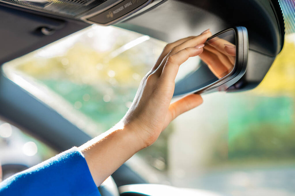 Κοντινό χέρι γυναικών ρυθμίζοντας το κάτοπτρο οδήγησης - Φωτογραφία, εικόνα