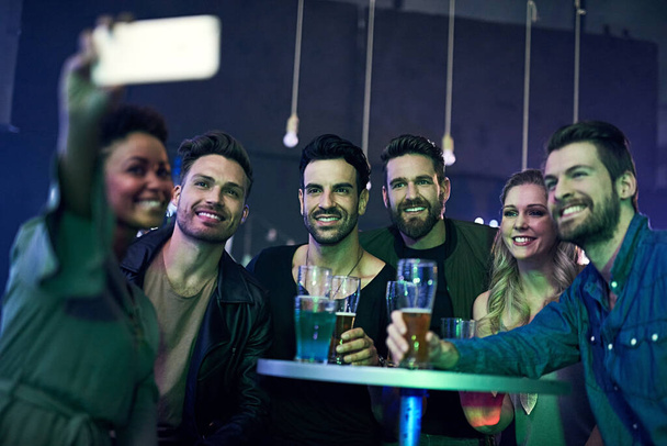 Remembering an awesome night out. Shot of a group of young friends taking a selfie together while partying in a nightclub. - Foto, imagen