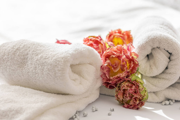 Close-up, white terry bath towels and flowers. - Foto, imagen