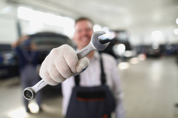 Servicemitarbeiter halten Schraubenschlüssel, Metallwerkzeug, um Fahrzeug zu reparieren - Foto, Bild