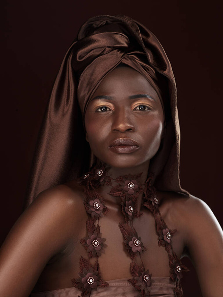 Some say head wrap, I say crown. Studio portrait of an attractive young woman posing in traditional African attire against a black background. - Fotografie, Obrázek
