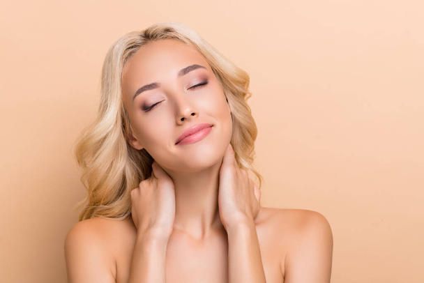 Portrait of attractive dreamy shine wavy-haired girl touching pure neck massaging enjoying isolated over beige pastel color background - Photo, Image
