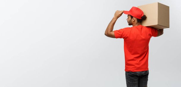 Delivery Concept - back view of Handsome African American delivery man with box package. Isolated on Grey studio Background. Copy Space. - Foto, Imagem