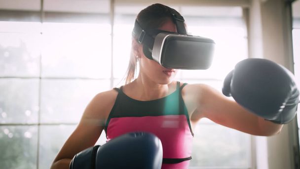Young Asian woman wearing virtual reality glasses while working out at home. - Fotó, kép