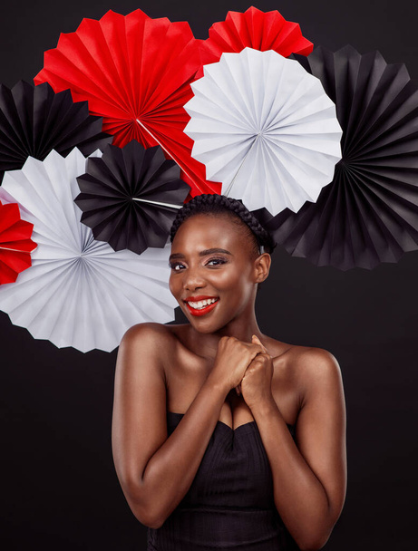 Nothing says Japan like a beautifully folded fan. Studio shot of a beautiful young woman posing with a origami fans against a black background. - Foto, imagen