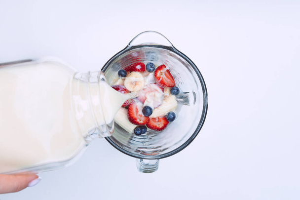 Making smoothie or milkshake in blender. Pouring milk in a blender with fruits. Vegan smoothie with plant based milk - Foto, immagini