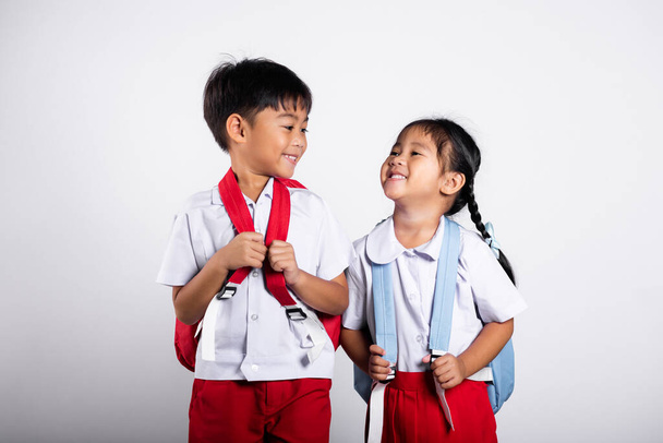 Two Asian student kid girl boy schoolchildren brother sister smile happy wear student thai uniform red pants skirt in studio shot isolated on white background, Portrait little children girl preschool - Zdjęcie, obraz