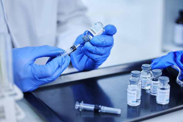 Час вакцинуватися. Обрізаний знімок невпізнаваного вченого, який використовує шприц для отримання вакцини від ковадла 19 з пляшки в лабораторії
. - Фото, зображення