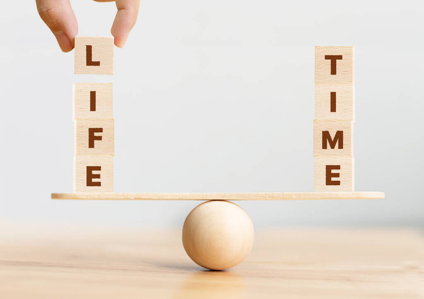 Koncepcja równowagi czasu życia. Drewniany sześcian z napisem LIFE i TIME na huśtawce - Zdjęcie, obraz