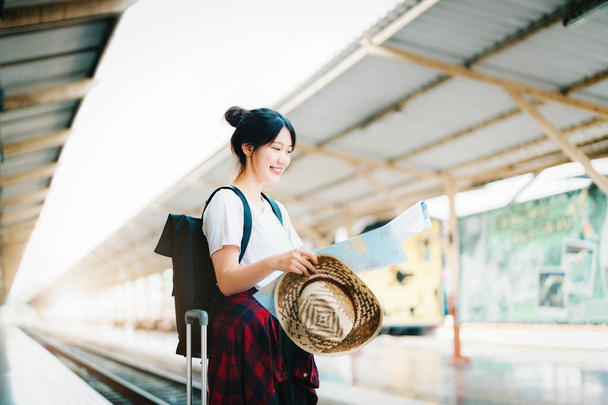 καλοκαίρι, χαλαρώστε, διακοπές, ταξίδια, πορτρέτο ενός χαριτωμένο κορίτσι της Ασίας κοιτάζοντας ένα χάρτη για να σχεδιάσετε ένα ταξίδι, ενώ περιμένει στο σιδηροδρομικό σταθμό. - Φωτογραφία, εικόνα