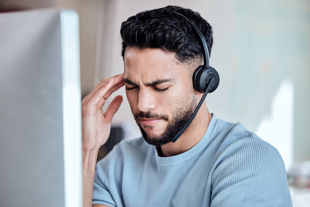 This customer is testing my patience. Shot of a young businessman working in a call center experiencing a headache. - Foto, imagen