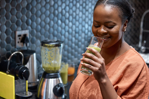 Eat better, your body will thank you. Shot of a young woman making a healthy smoothie at home. - Photo, Image