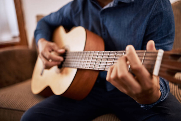 Time to tune up these skills. Shot of a man practicing his guitar skills at home. - Foto, imagen